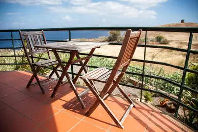 a wooden table and two chairs sitting on a balcony at Casa Da Atalaia in Caniço