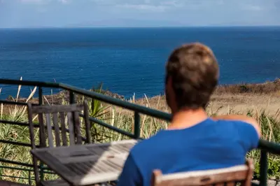 a person sitting on a bench looking at the ocean at Casa Da Atalaia in Caniço
