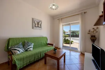 a living room with a green couch and a sliding glass door at Casa Bege T1 in Burgau