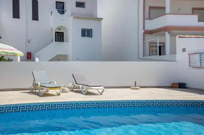 a table with chairs and a green umbrella on a balcony at Villas Brites nº5 in Burgau