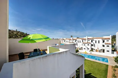a balcony with chairs and an umbrella on a building at Villas Brites nº5 in Burgau