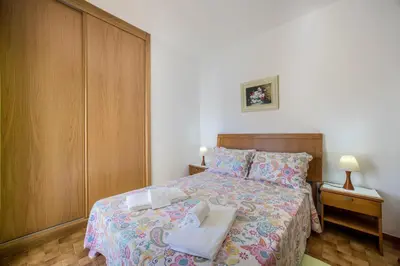 a bedroom with a bed and two tables and a chair at Villas Brites nº3 in Burgau