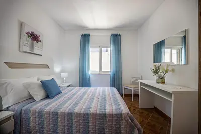 a bedroom with a bed with blue curtains and a desk at Casa Fernandes in Burgau