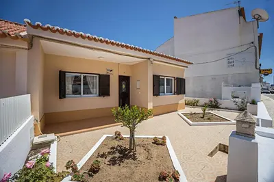 a house with a white fence next to a street at Casa Fernandes in Burgau