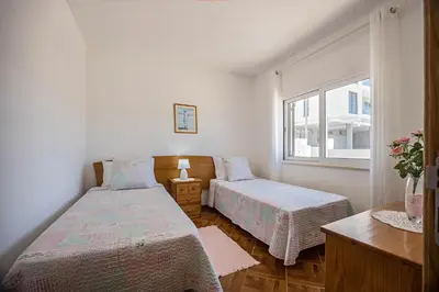 a bedroom with two beds and a desk and a mirror at Casa Fernandes in Burgau