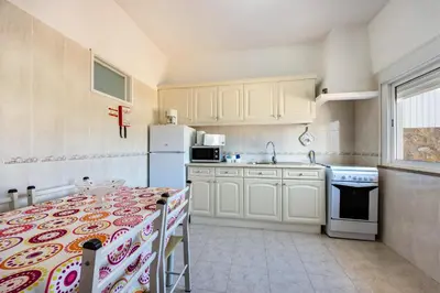 a kitchen with a table and a white refrigerator at Villas Brites nº1 in Burgau