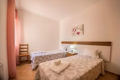 a hotel room with two beds and a chair at Casa Bege T2 in Burgau