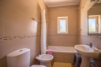a white kitchen with white cabinets and a sink at Casa Bege T2 in Burgau