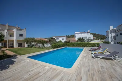 a swimming pool in a villa with two chairs at Casa Bege T2 in Burgau