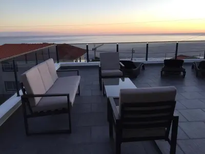 a patio with chairs and tables and a view of the ocean at Calheta Ocean View Family Apartment - Air Condition in Estreito da Calheta