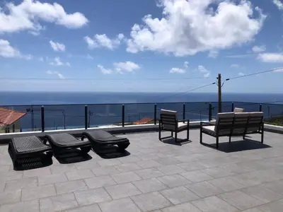 a patio with benches and a view of the ocean at Calheta Ocean View Family Apartment - Air Condition in Estreito da Calheta