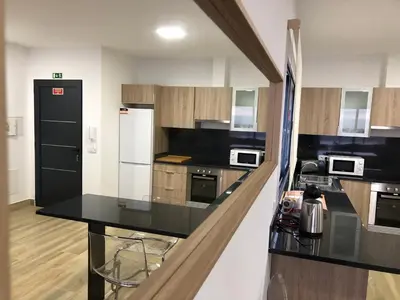 a kitchen with a black counter top and wooden cabinets at Calheta Ocean View Family Apartment - Air Condition in Estreito da Calheta