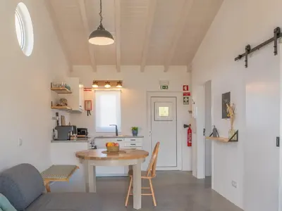 a living room with a table and a kitchen at Ao Sabor do Vento (+12 ) in Aljezur