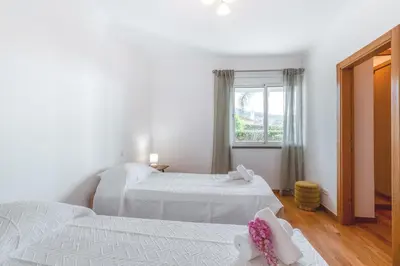 two beds in a white room with a window at Jardim do Jasmineiro by Amazing Madeira in Funchal