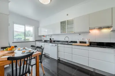 a kitchen with white cabinets and a table with chairs at Jardim do Jasmineiro by Amazing Madeira in Funchal