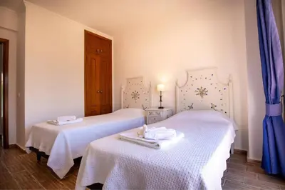 two white beds in a room with blue curtains at Villa Carraig in Luz