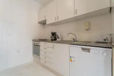 a white kitchen with white cabinets and a sink at FLH Funchal Studio with Balcony in Funchal