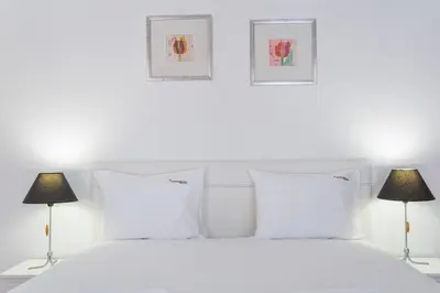 a bedroom with a white bed with two lamps at FLH Funchal Studio with Balcony in Funchal