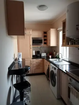a kitchen with wooden cabinets and a washer and dryer at Machico Beach Comfort in Machico