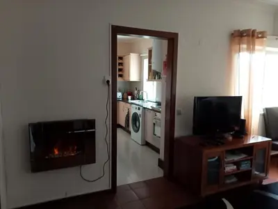 a living room with a fireplace and a kitchen at Machico Beach Comfort in Machico