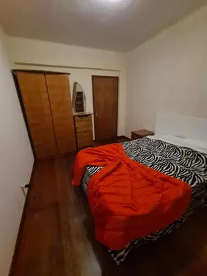 a bedroom with a bed with an orange blanket on it at Machico Beach Comfort in Machico