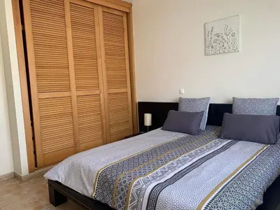 a bedroom with a bed and a wooden closet at Porto Santo Casa Dourada in Porto Santo