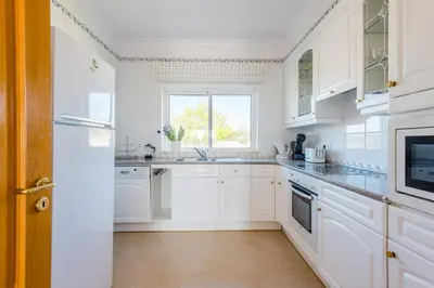 a white kitchen with white cabinets and a window at Casa Ocean Golf - Boavista Resort in Lagos