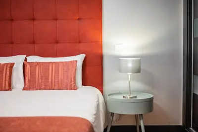 a bedroom with a red headboard and a bed with a lamp at Villa Vacuna by Amazing Madeira in Funchal