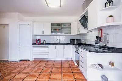a kitchen with white cabinets and a tile floor at Vila Crerital - By Wehost in São Gonçalo