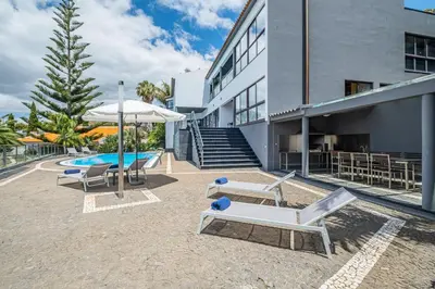 a patio with chairs and an umbrella next to a building at Vila Crerital - By Wehost in São Gonçalo