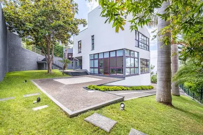 an exterior view of a white house with trees at Vila Crerital - By Wehost in São Gonçalo