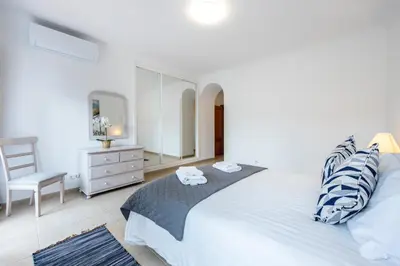 a bedroom with a bed with a mirror and a chair at Casa Ensolarada in Budens
