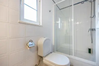 a white bathroom with a toilet and a shower at Casa Ensolarada in Budens