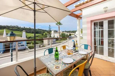 a patio with a table and chairs and an umbrella at Casa Ensolarada in Budens