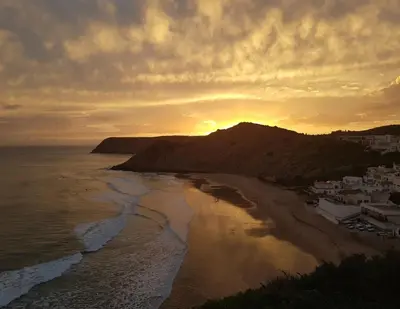 a sunset over a beach with a mountain in the background at Casa da Praia 1 in Budens