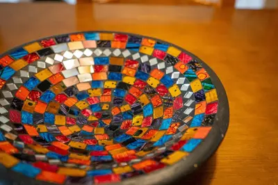 a colorful mosaic plate sitting on a wooden table at Casa da Praia 2 in Budens
