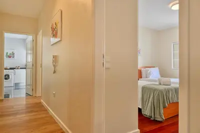 a room with a bed and a hallway with a kitchen at Nidia’s Place, a Home in Madeira in Machico