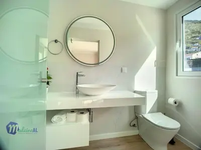 a white bathroom with a sink and a mirror at PEARLS BEACH VILLA in Porto Moniz