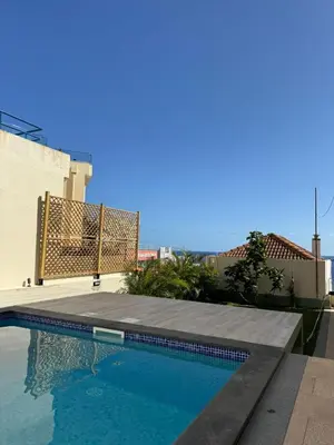 a swimming pool in front of a building at PEARLS BEACH VILLA in Porto Moniz