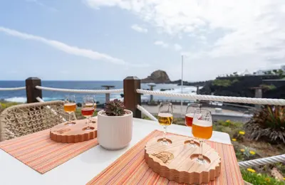 two glasses of wine on a table on a balcony at Aqua Natura Madeira in Porto Moniz