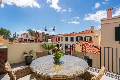 a table on a balcony with a view of a city at Casa Caetano by An Island Apart in Funchal