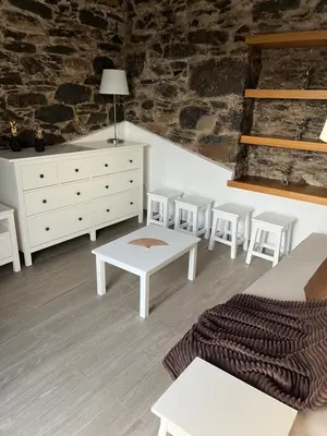 a living room with white furniture and a brick wall at Casa do Avô in Ponta do Sol