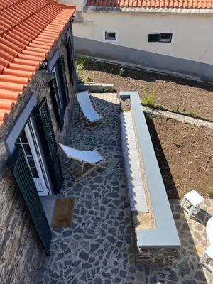 two chairs and a bench next to a building at Casa do Avô in Ponta do Sol