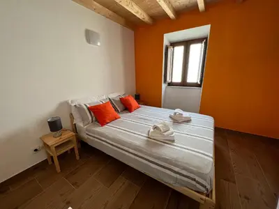 a bedroom with a bed with orange walls and a window at Casa Arenga in Almádena