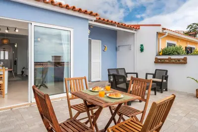 a patio with a wooden table and chairs and a house at Terrace Vila II by An Island Apart in Santa Cruz