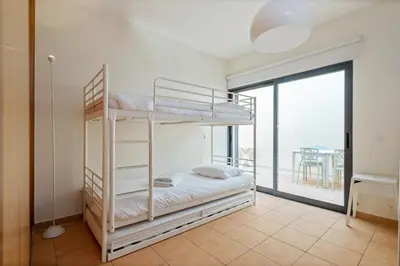 a bedroom with two bunk beds and a balcony at Casa das Pedras Pretas - By WeHost in Porto Santo