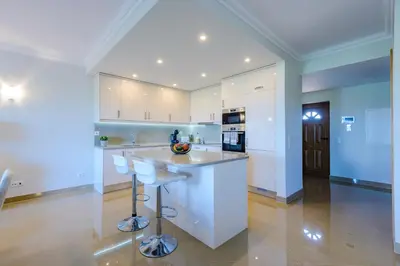 a kitchen with white cabinets and bar stools at Boavista Golf and Spa Resort - Bayview in Lagos