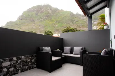 a balcony with chairs and a view of a mountain at Village Center Two Bedroom Apartment in Porto Moniz