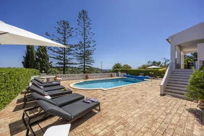a group of lounge chairs next to a swimming pool at CoolHouses Algarve Lagos, 4 bed single-story House, pool and amazing panoramic views, Casa Fernanda in Lagos
