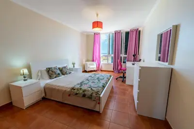 a bedroom with a bed and a room with pink curtains at Vista Mar in Porto Santo